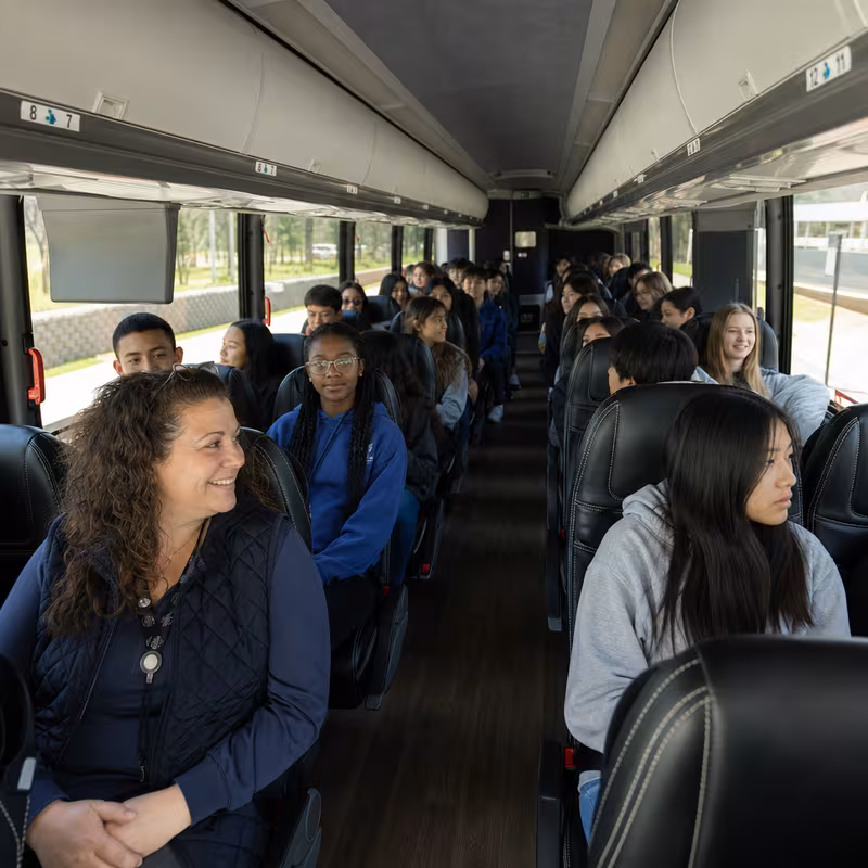 Group boarding a white charter bus for School Transportation transportation in Anaheim